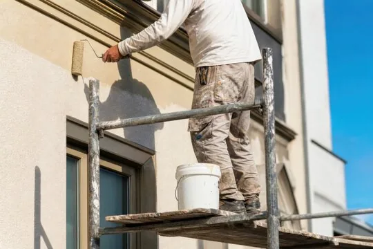 Painter rolling a stucco exterior from scaffolding in the San Fernando Valley